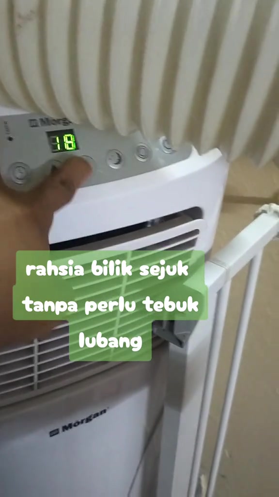 Tangan menekan butang panel portable aircond Morgan dengan paparan suhu 18 dan hose besar di bahagian atas unit