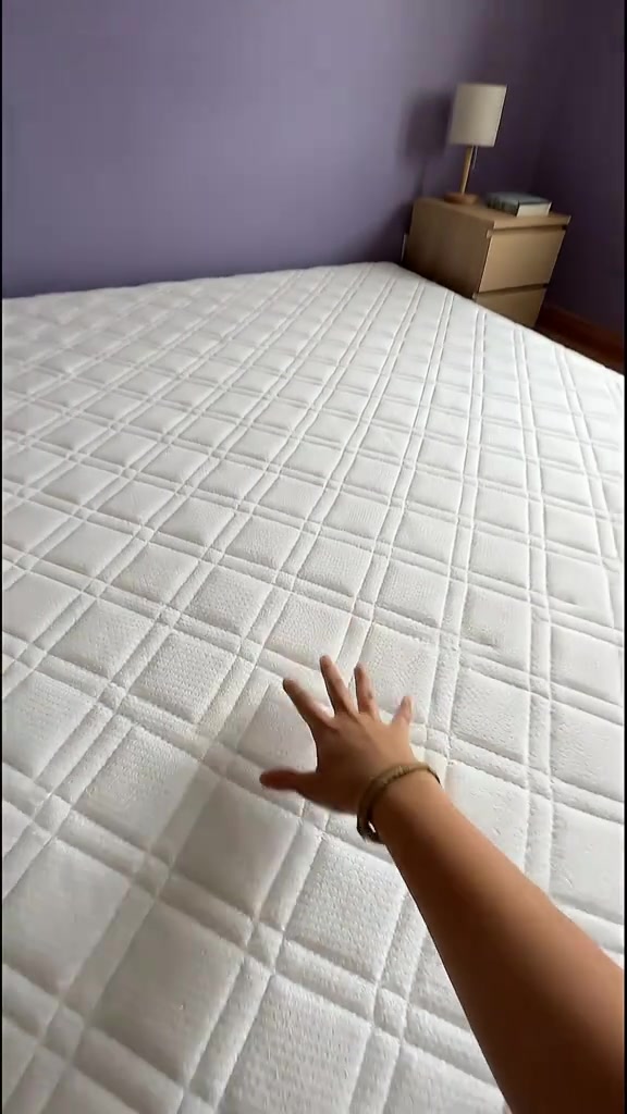 Tangan menekan permukaan tilam quilted putih untuk uji kelembutan dan sokongan