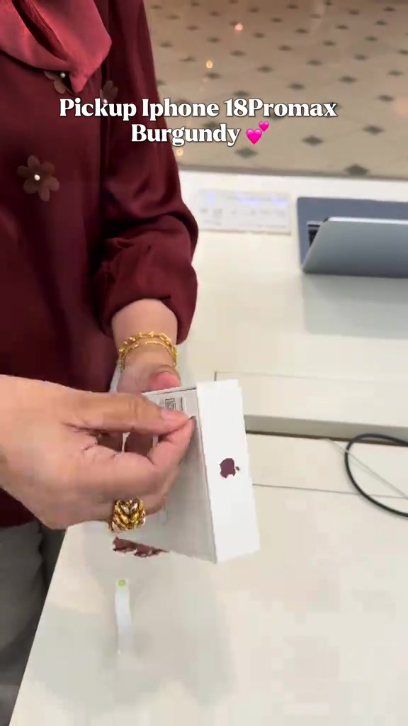 Tangan pelanggan membuka kotak iPhone 18 Pro Max berwarna burgundy yang masih bersegel di kaunter jualan