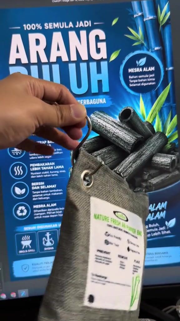 Tangan angkat beg arang bambu pada cangkuk logam dengan latar foto batang arang buluh