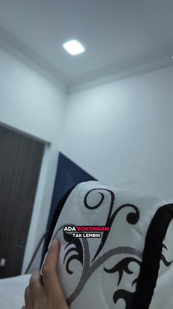 Tangan memegang penjuru tilam bercorak bunga hitam putih dari dekat, menunjukkan tepi dan jahitan tilam