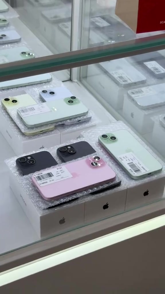 Rak kaca kedai dengan beberapa unit iPhone berwarna atas kotak Apple, satu unit berlabel sticker ZP SET