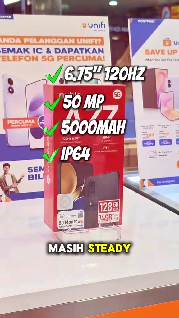 Kotak merah nubia A77 5G dengan sticker 128GB ROM dan 14GB RAM, bertanda skrin 6.75 inci 120Hz, kamera 50MP, bateri 5000mAh dan IP64, di atas meja pameran kedai