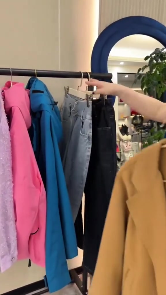Tangan menggantung seluar pada penyangkut klip di bar rak baju besi