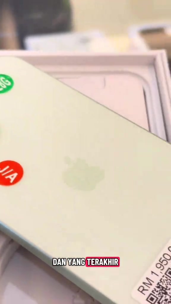 iPhone 15 warna hijau dengan tag harga RM1,950 dan pelekat bulat hijau pada badan phone