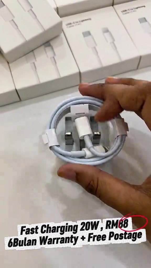 Tangan memegang kabel pengecas USB-C ke Lightning bergulung dengan kotak aksesori di latar dan kapsyen Fast Charging 20W RM88, waranti 6 bulan serta pos percuma