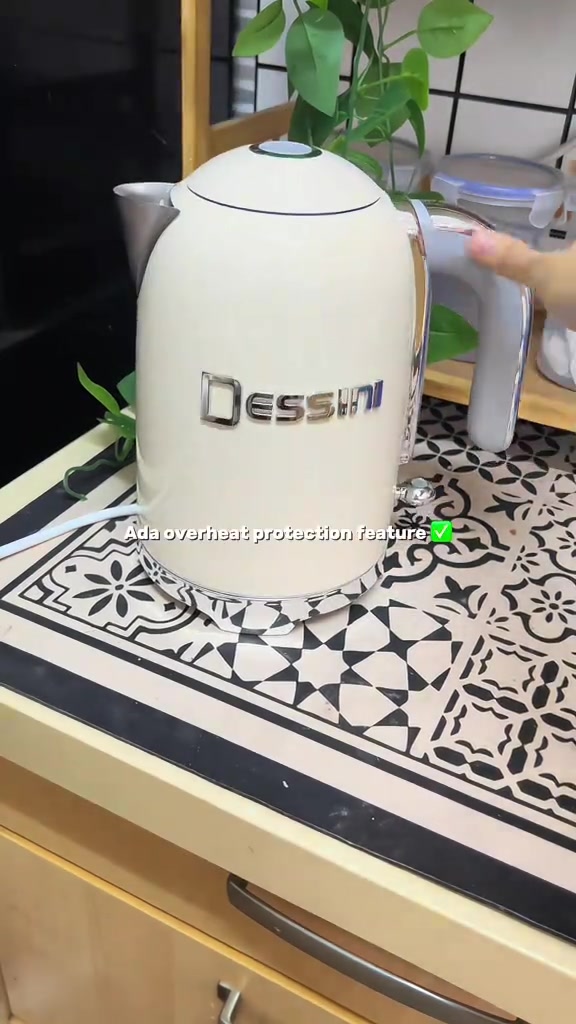 Cerek elektrik Dessini warna krim di atas counter dapur bercorak dengan keterangan fitur perlindungan overheat