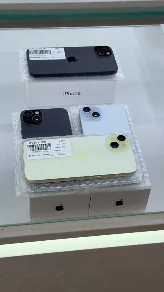 Unit iPhone atas rak kedai dengan label sticker bertulis 16PLUS 128GB dan J SET