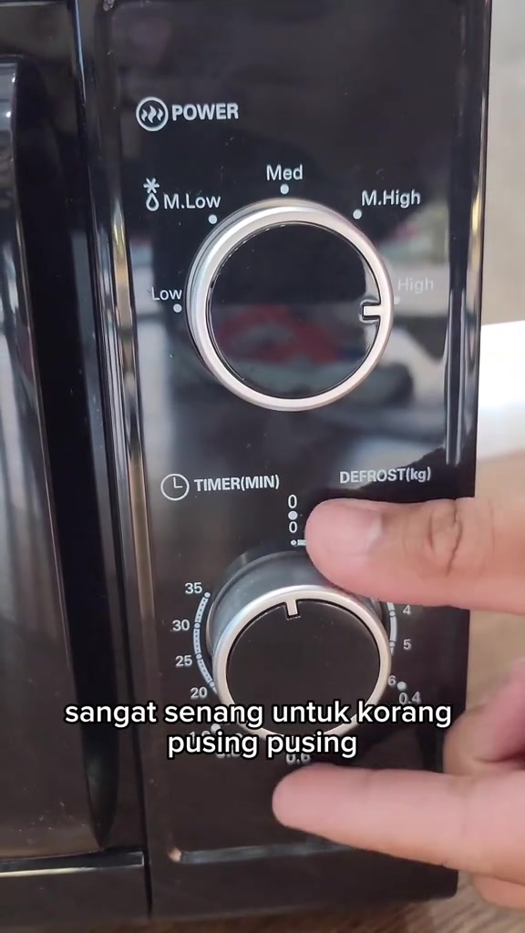 Tangan memusing knob timer dan defrost ikut berat pada panel microwave mekanikal hitam