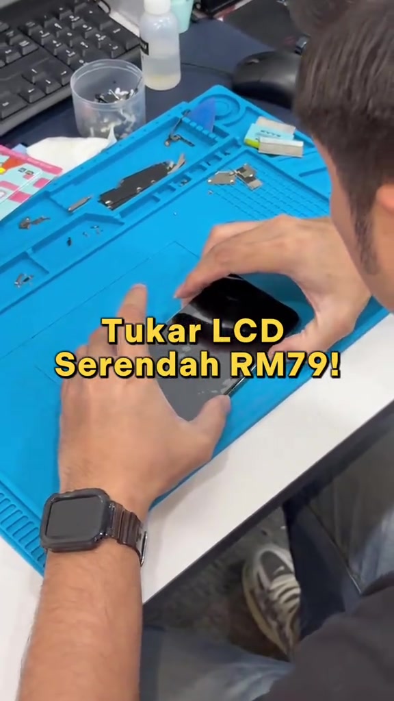 Tangan juruteknik memasang semula skrin iPhone di atas mat repair biru dengan kapsyen tukar LCD serendah RM79