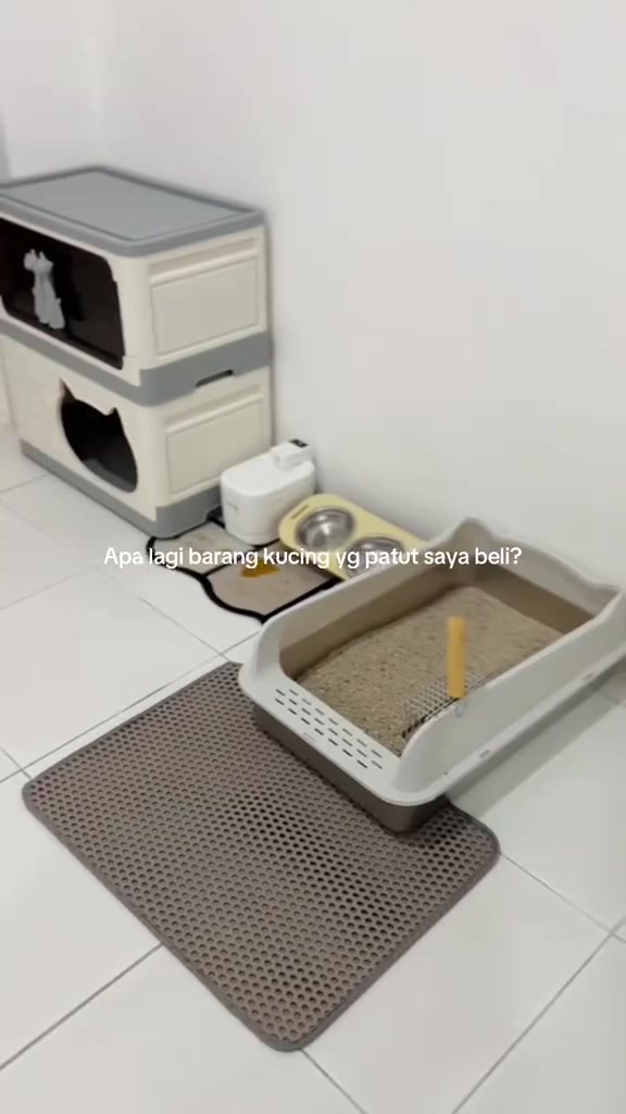 Sudut kucing lengkap dalam rumah: rumah kucing bertingkat, water fountain, mangkuk makanan, kotak pasir dan litter mat di lantai jubin