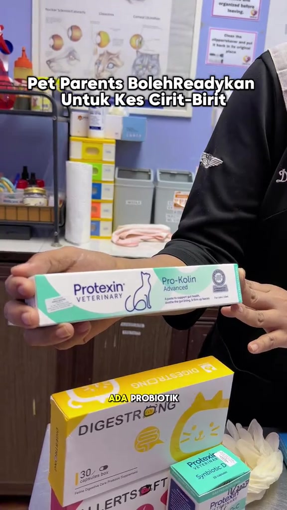 Tangan memegang kotak probiotik Protexin Pro-Kolin di meja klinik bersama kotak suplemen lain