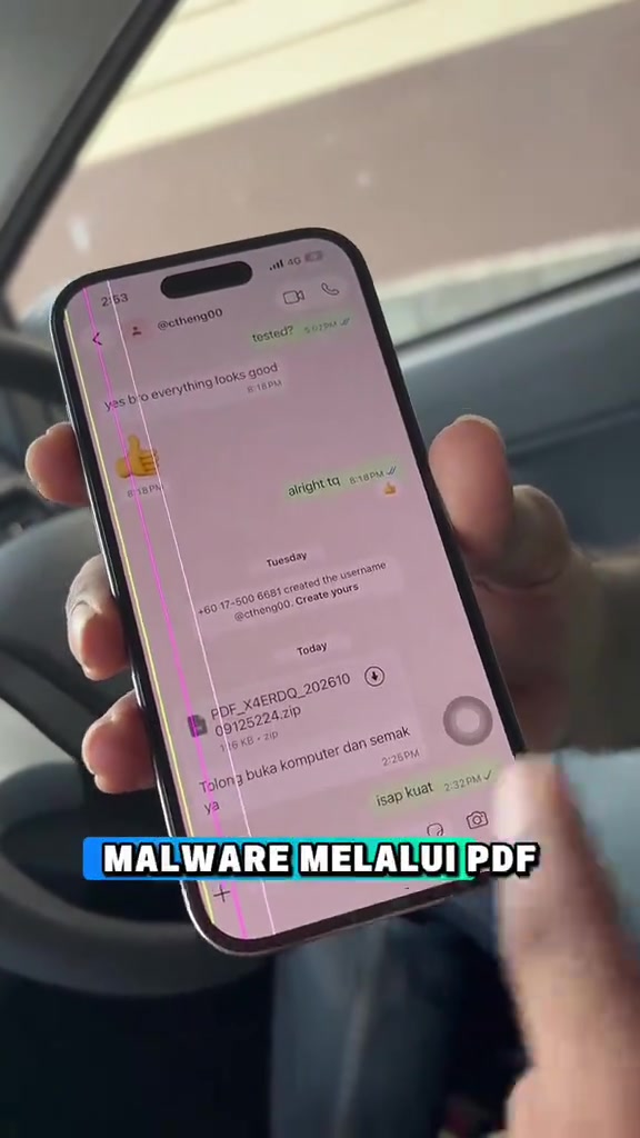 Tangan memegang telefon yang membuka chat WhatsApp dengan fail bernama PDF_X4ERDQ_20261009125224.zip dan mesej meminta membuka komputer untuk semak