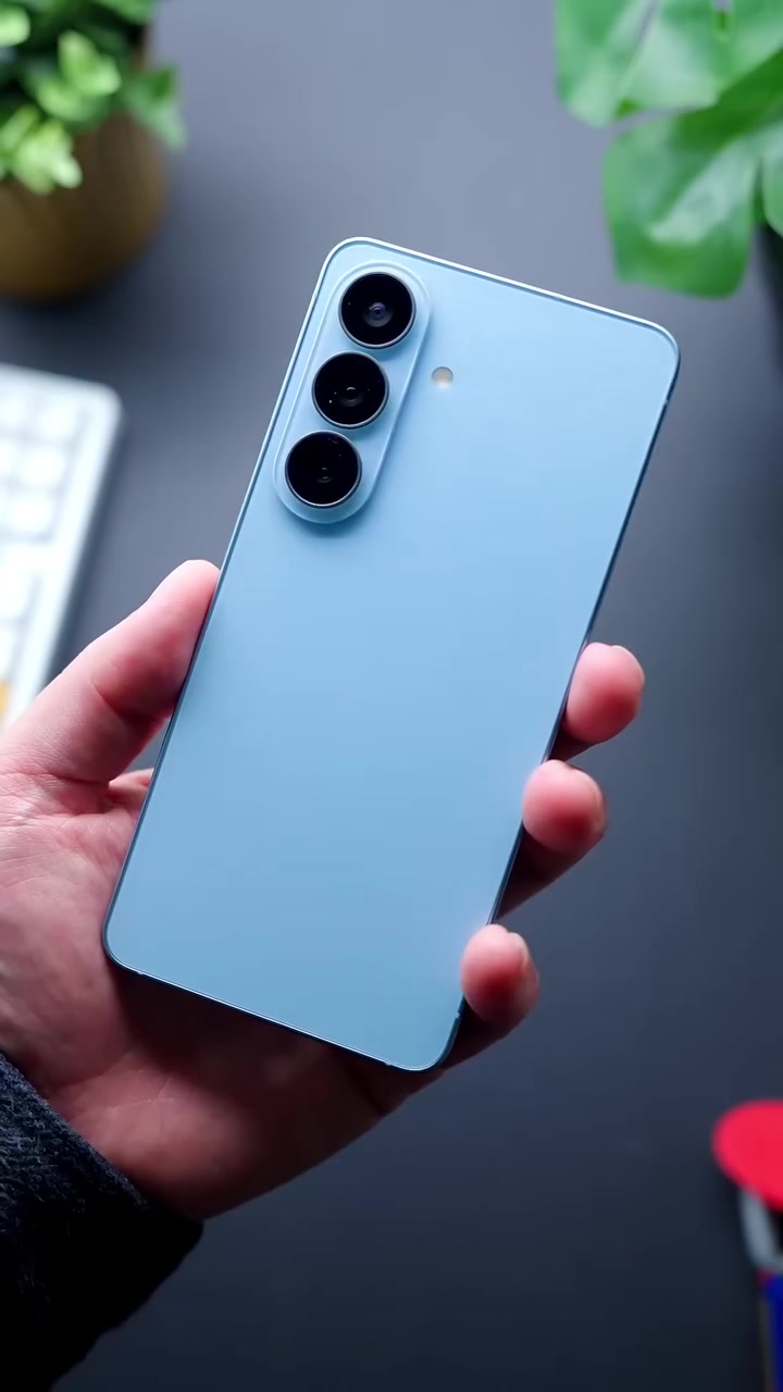 Galaxy S26 warna biru muda dipegang satu tangan, pandangan belakang dengan tiga kamera