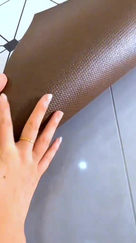 Tangan menyelak sudut alas kaki PVC coklat bertekstur menunjukkan permukaan belakangnya yang kalis air