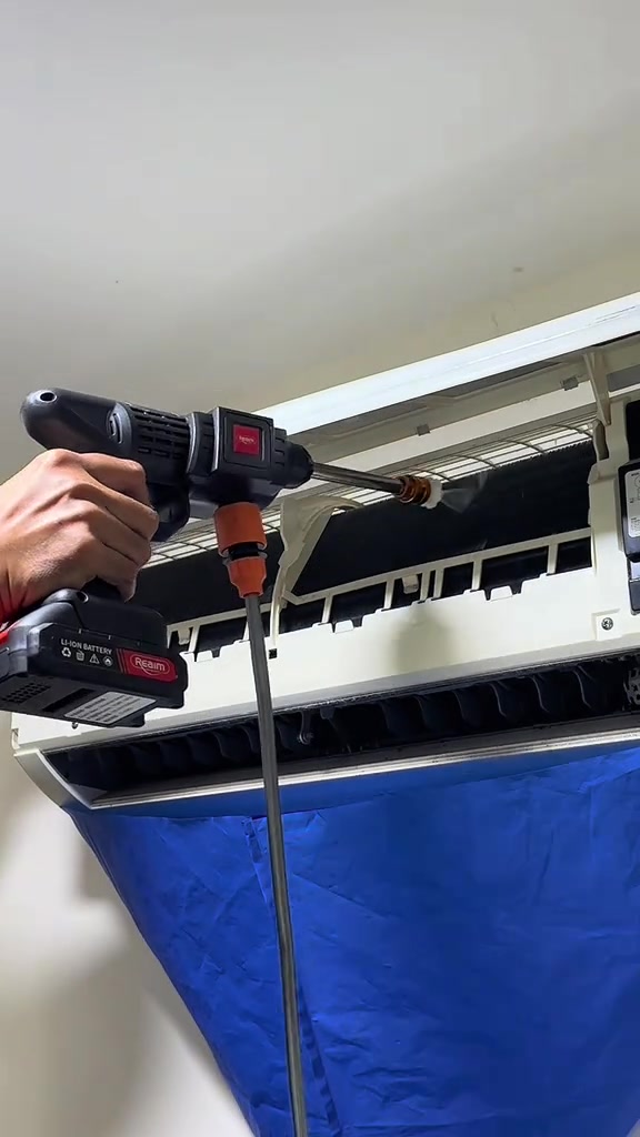 Penyembur tekanan tanpa wayar membilas coil aircond sementara wash cover biru menadah air di bawah unit