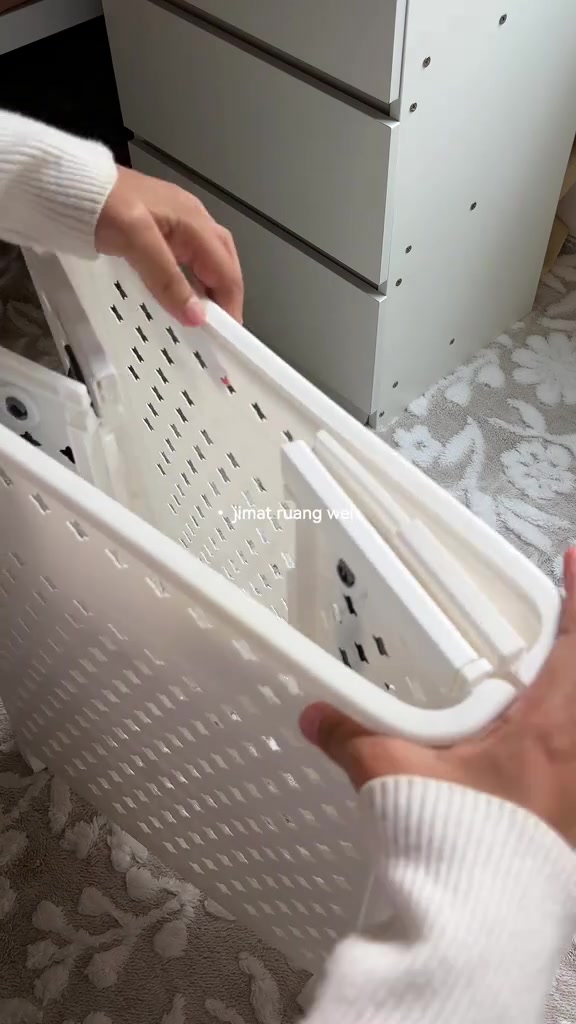 Tangan melipat rata panel bakul baju plastik putih berlubang menjadi bentuk nipis