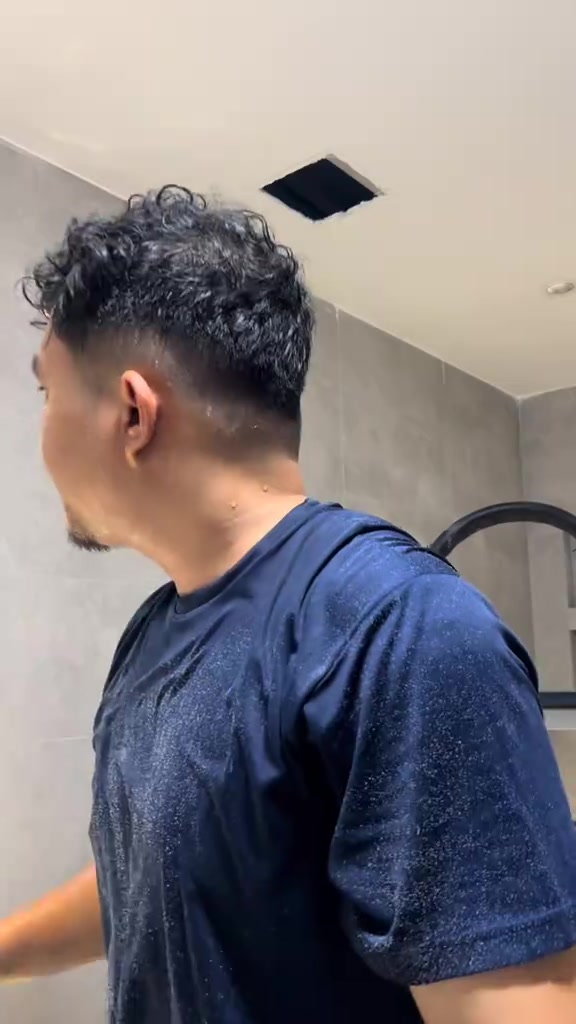 Lubang segi empat siap dipotong pada siling bilik air untuk pemasangan exhaust fan, seorang lelaki berdiri berhampiran dilihat dari belakang