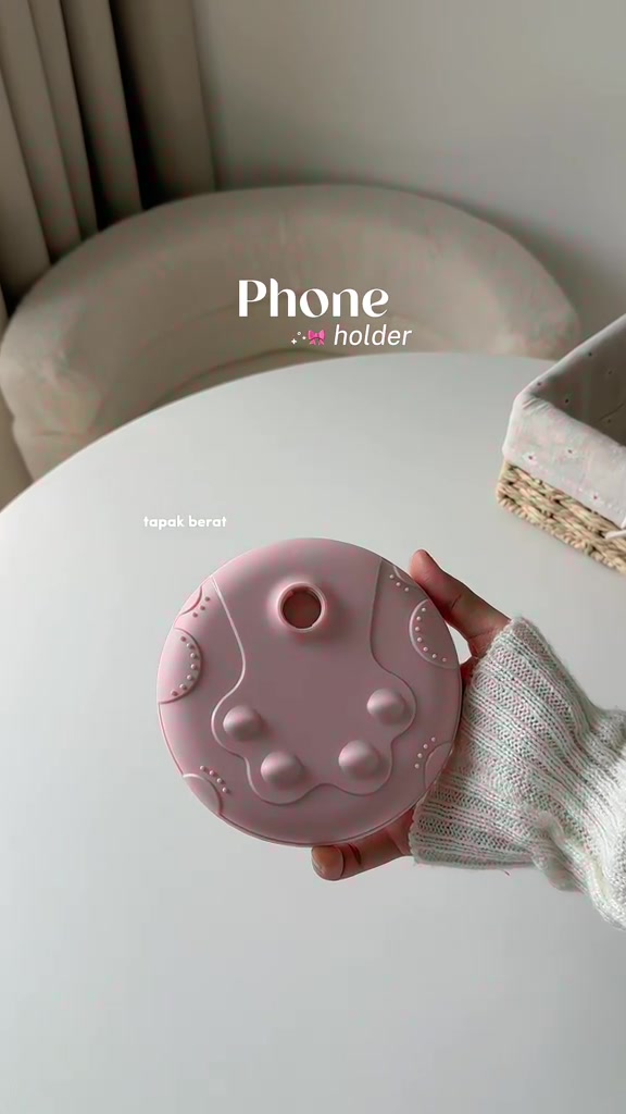 Tangan memegang tapak bulat berat stand telefon merah jambu dari sebelah bawah