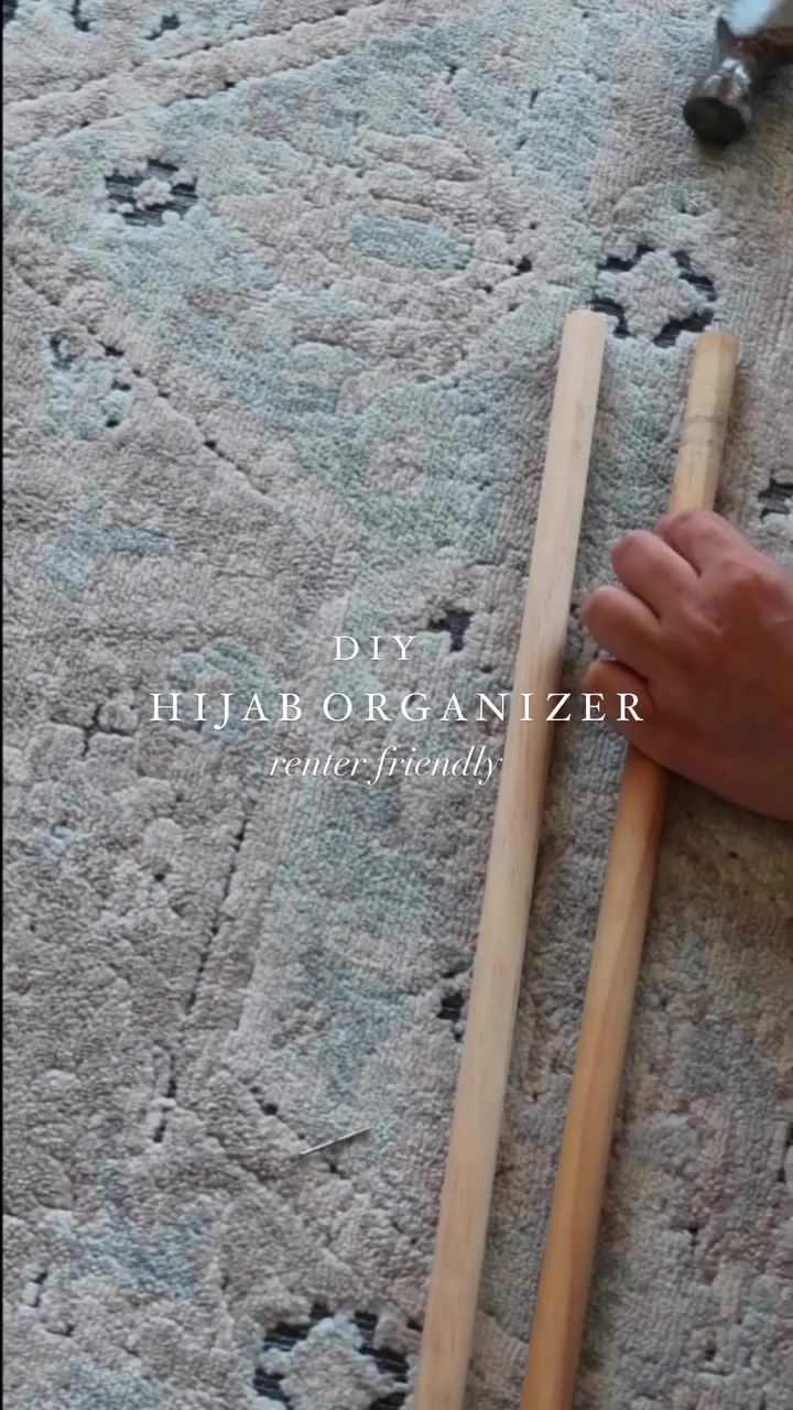 Dowel kayu untuk DIY rail hijab organizer diletak atas permaidani bersama tangan memegangnya