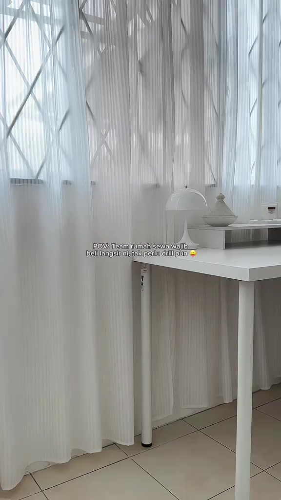 Langsir sheer putih menutup tingkap berjeriji di belakang meja kerja putih, dipasang tanpa tebuk dinding