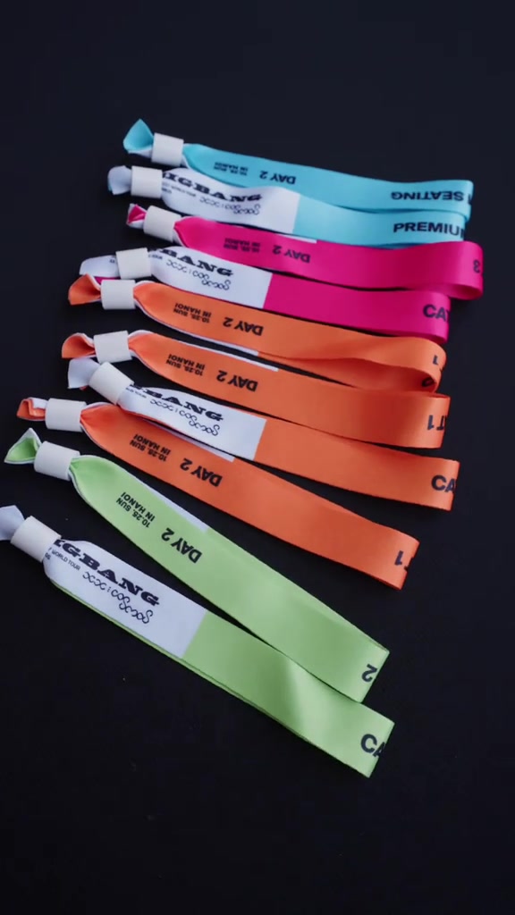 Các vòng tay vải phân màu theo hạng vé hai đêm concert BIGBANG tại Hà Nội, in chữ DAY 2 và tên hạng, xếp trên nền đen