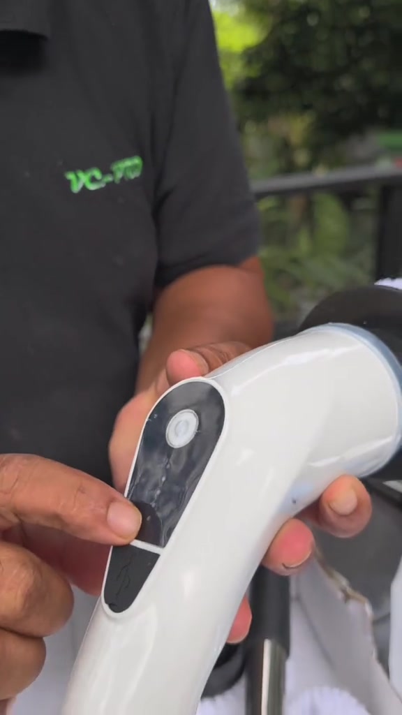 Tangan menekan panel butang hitam pada pemegang putih berus elektrik cordless