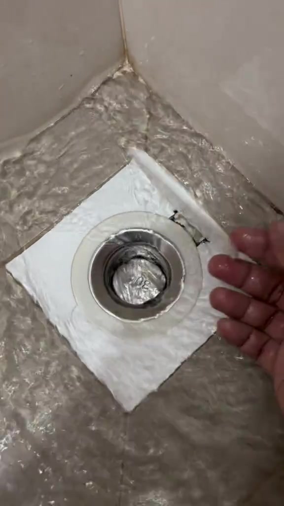 Tangan terbuka di sisi penutup floor trap yang tertutup rapat semula selepas air lalu di lantai jubin basah