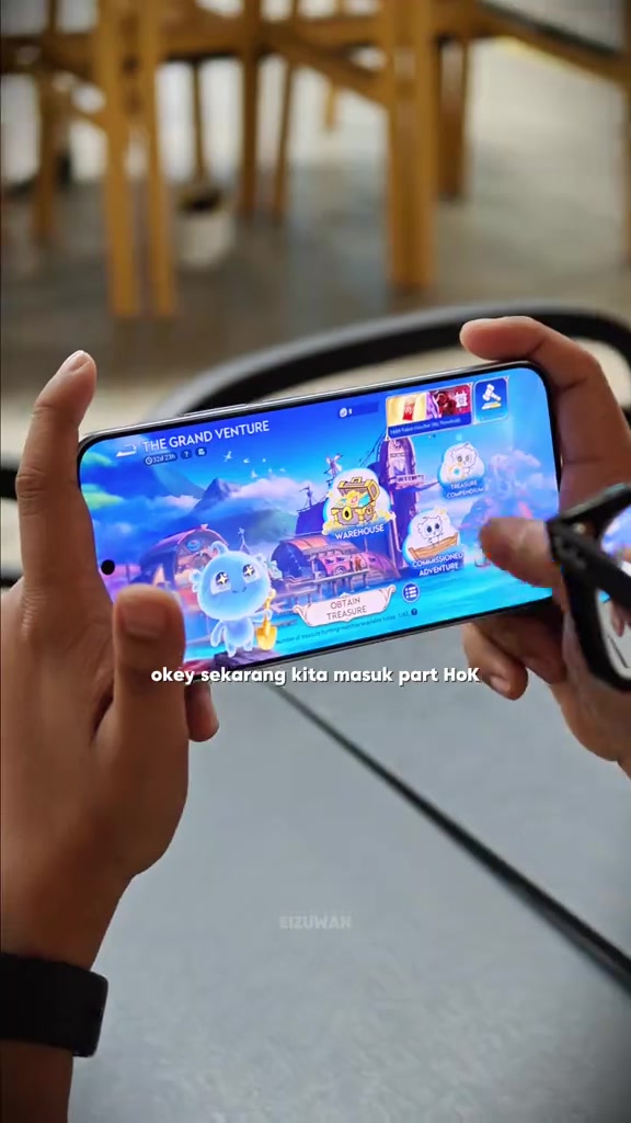Dua tangan memegang telefon melintang sedang main game Honor of Kings