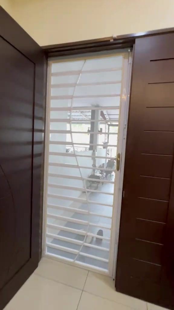 Skrin jaring nyamuk berbingkai putih menutup penuh ruang pintu di antara dua pintu kayu coklat
