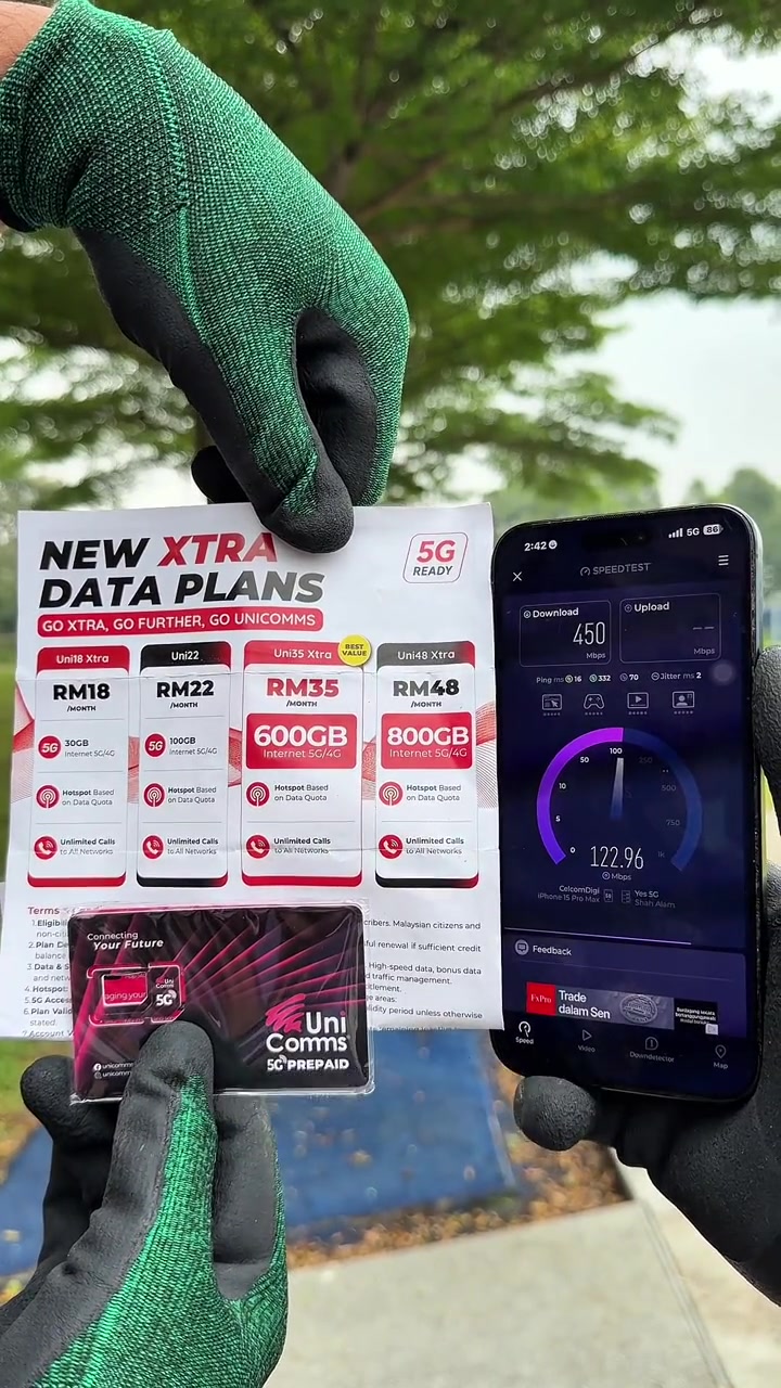 Helai senarai pelan UniComms dan pek SIM dipegang sebelah telefon yang memaparkan aplikasi speedtest dengan bacaan muat turun 450 Mbps dan label rangkaian CelcomDigi pada skrin