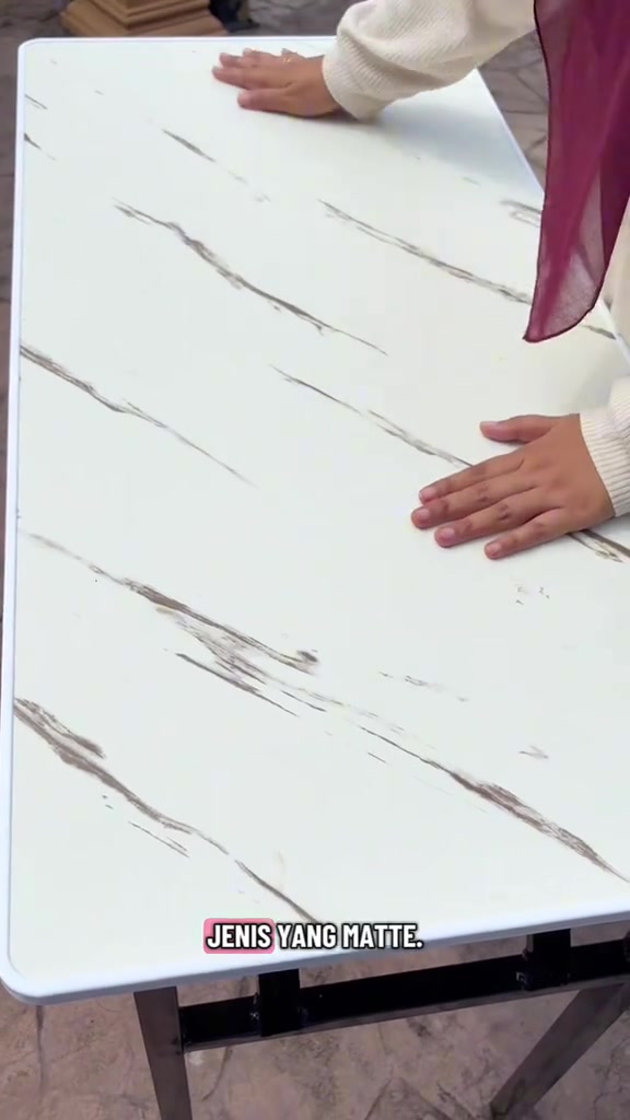 Dua tangan menekan permukaan meja lipat corak marble matte untuk uji kekukuhan