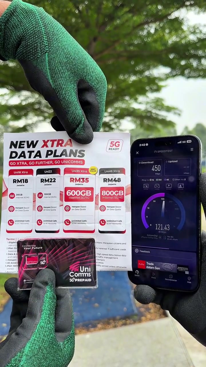 Helai senarai pelan UniComms Xtra RM18 hingga RM48 dan pek SIM 5G Prepaid dipegang bersama telefon memaparkan keputusan speedtest muat turun 450 Mbps, dengan ruangan terma kecil kelihatan di bahagian bawah helai