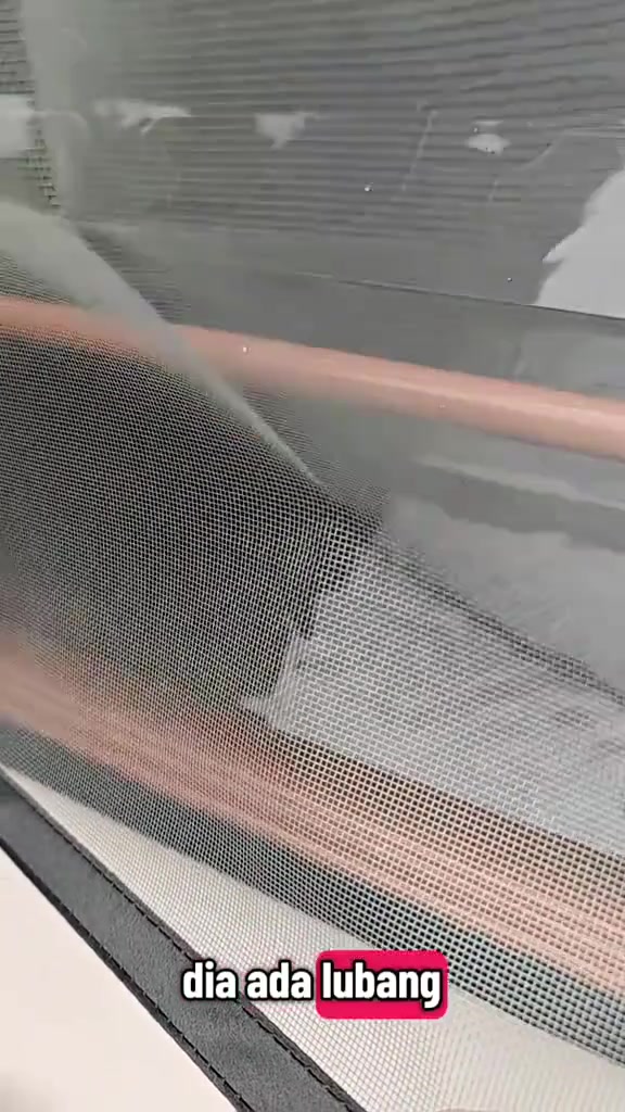 Close-up anyaman jaring nyamuk fiberglass kelabu yang halus dengan tepi jahitan hitam