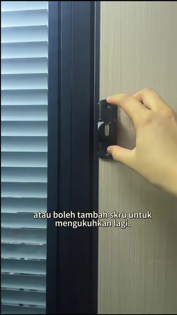 Tangan menekan selak pelekat hitam pada frame pintu sebagai lapisan kunci tambahan