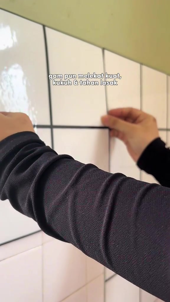 Dua tangan menekan kepingan wallpaper pelekat grid putih ke dinding