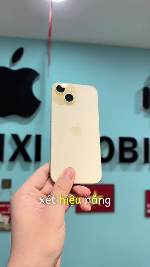 Mặt lưng iPhone 15 màu vàng cầm trên tay trước tường cửa hàng