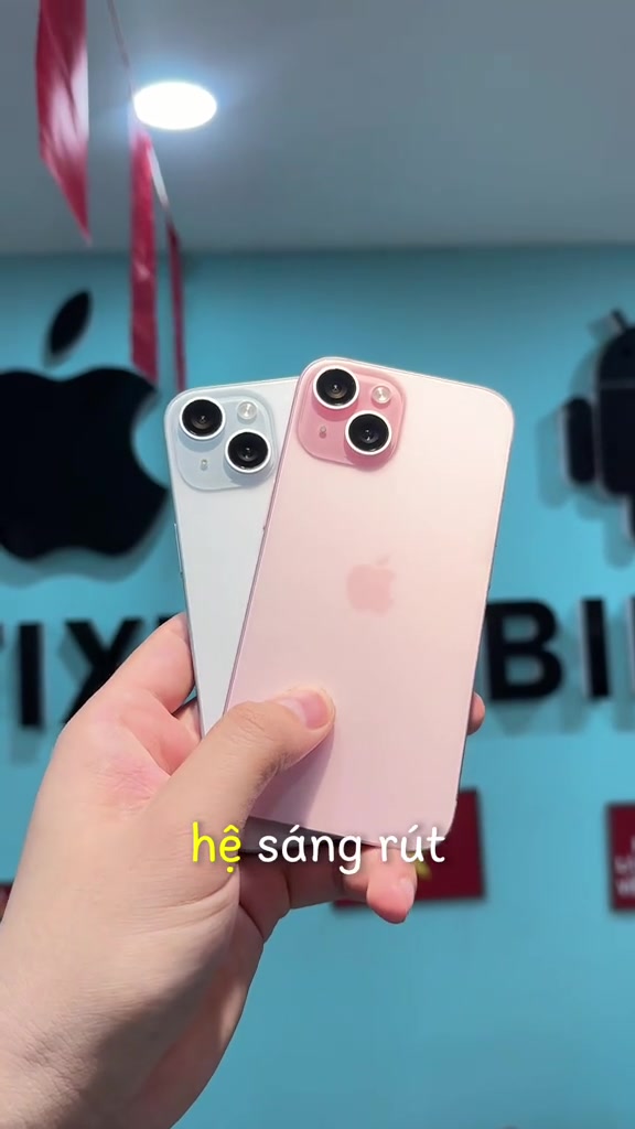 Hai chiếc iPhone 15 màu xanh và màu hồng cầm trên một tay để soi ngoại hình