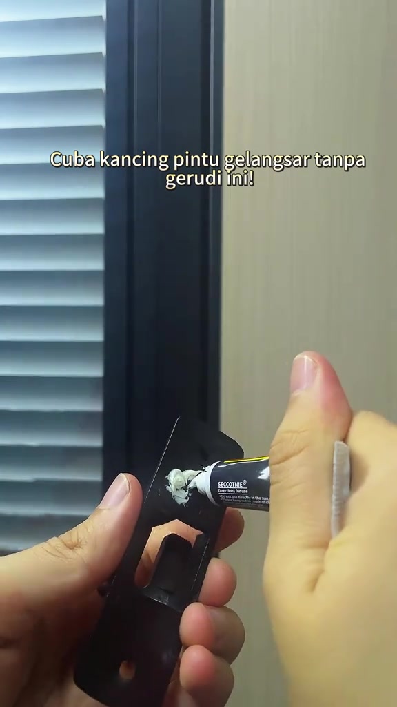 Tangan menyapu gam pada selak pintu hitam sebelum dilekat tanpa tebuk