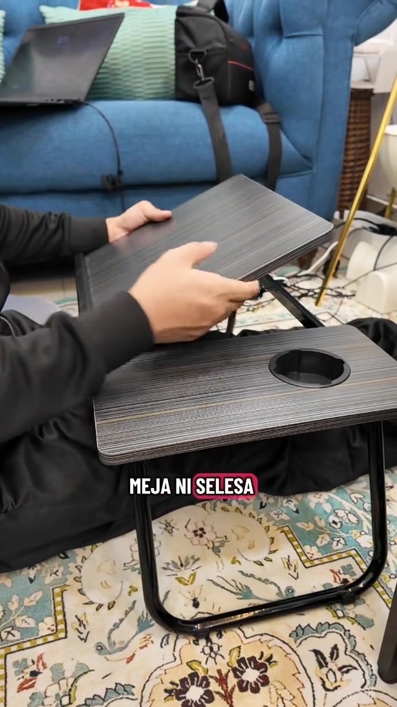 Tangan melipat permukaan meja laptop lipat berwarna gelap dengan cup holder bulat, di atas permaidani