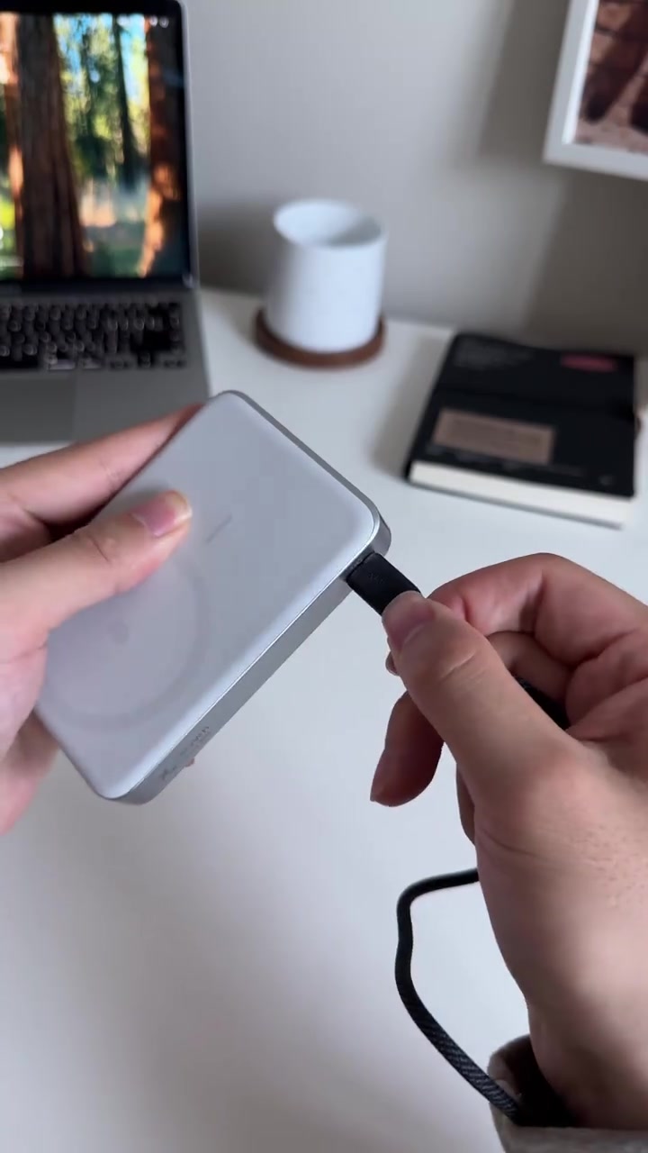 Hai tay cắm cáp USB-C vào cạnh cục sạc dự phòng MagGo màu trắng bạc đặt trên bàn làm việc
