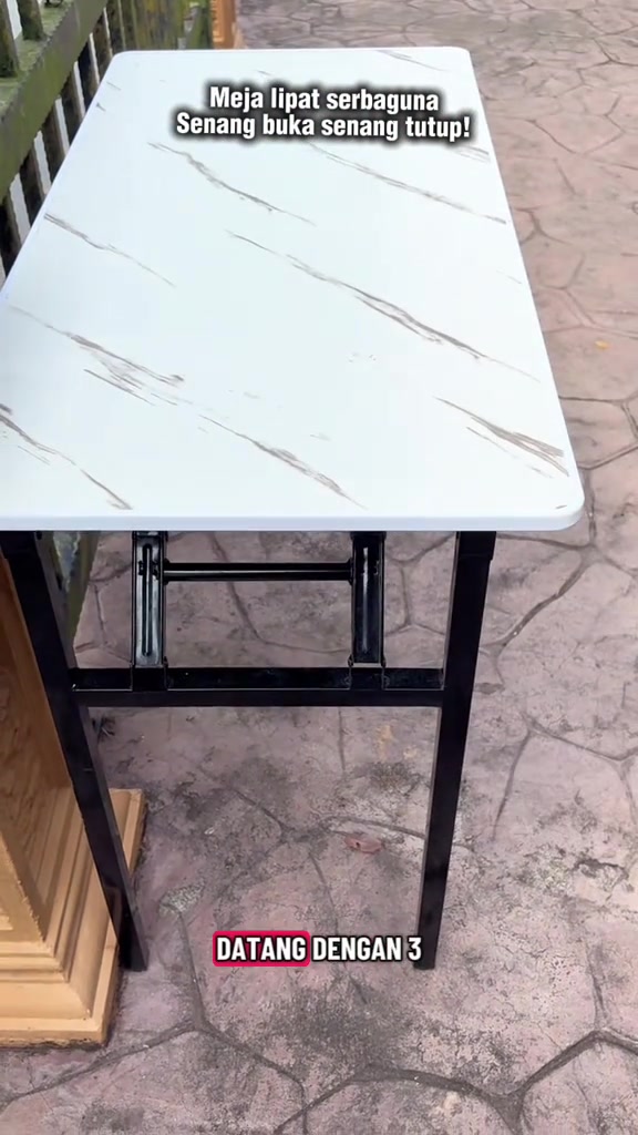 Meja lipat permukaan corak marble putih matte dengan kaki besi hitam, berdiri di lantai taman