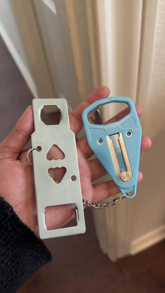 Tangan memegang plate logam berlubang dan klip plastik biru portable door lock yang bersambung dengan rantai kecil