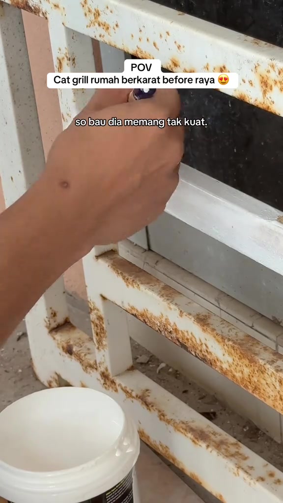 Tangan menyapu cat putih ke grill tingkap berkarat dengan tin cat waterbase di bawah