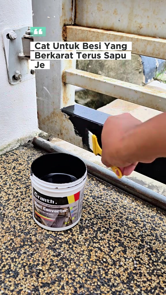 Tangan memegang berus kuning menyapu cat hitam ke atas palang pagar berkarat dengan tin rust converter di hadapan