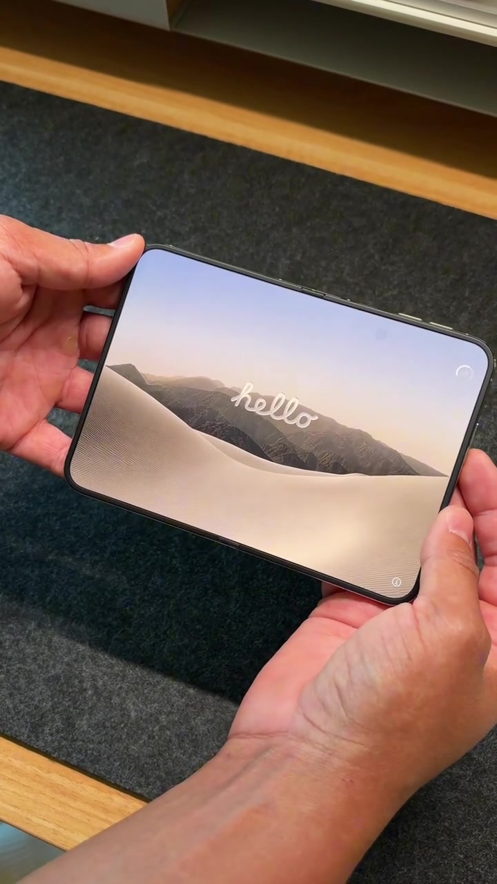 iPhone Duo terbuka penuh dipegang dua tangan dengan paparan dalam memaparkan skrin hello