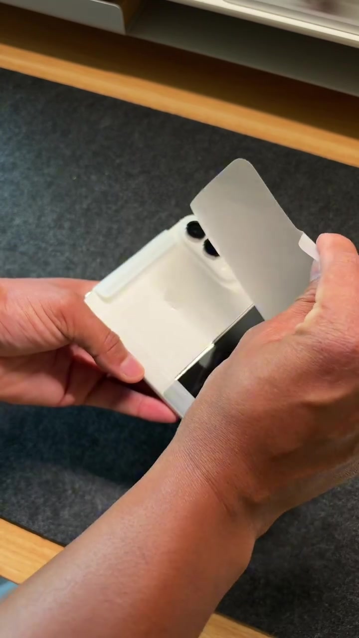 iPhone Duo warna putih sedang dibuka balutan kertas, bar kamera dua lensa kelihatan jelas