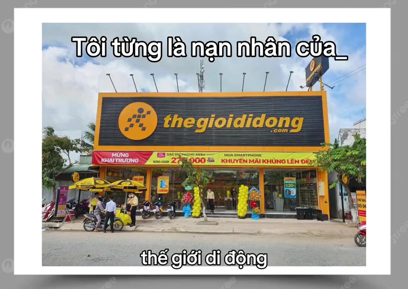 Mặt tiền cửa hàng Thế Giới Di Động với biển hiệu vàng đen cỡ lớn, phía trước có băng rôn khai trương và dù vàng