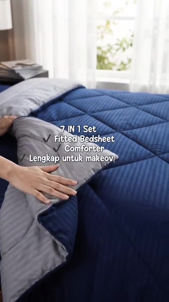 Tangan menyelak penjuru comforter biru berjalur menunjukkan senarai kandungan set 7 dalam 1 termasuk fitted bedsheet