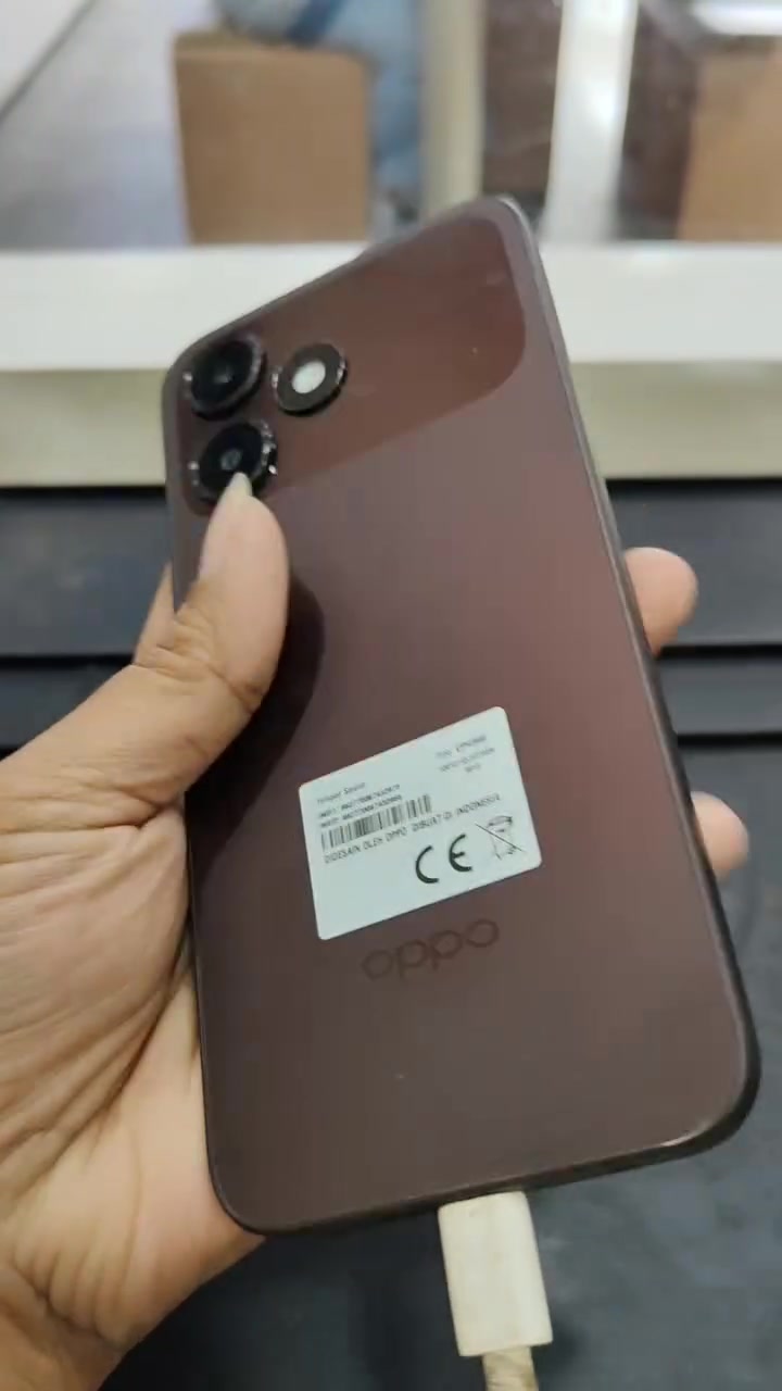 Bahagian belakang OPPO A6c warna brown dipegang tangan dengan pelekat label IMEI masih terlekat